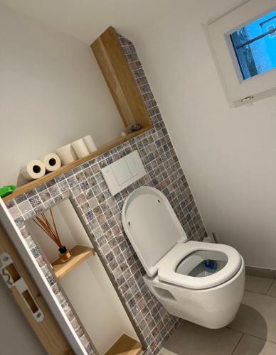 une salle de bain avec toilettes et un mur carrelé dans l'établissement MAISON CENTRE D'ARNAGE idéal 24h du Mans et Le Mans classic, à Arnage