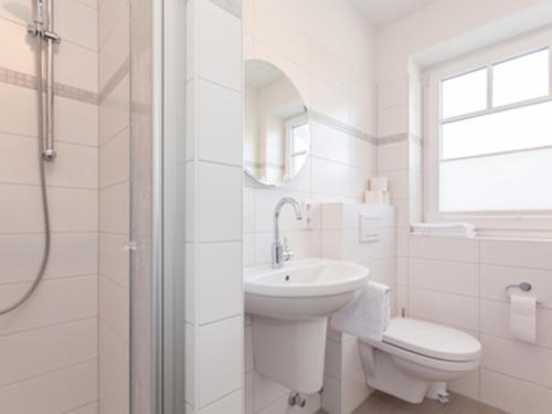 a white bathroom with a sink and a toilet at Ferienwohnung Julian in Hörnum