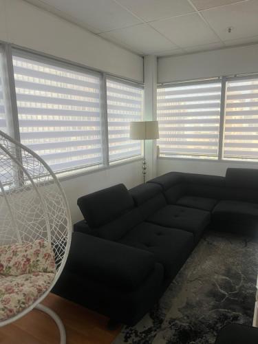 a black couch in a living room with windows at Colossume in Johannesburg