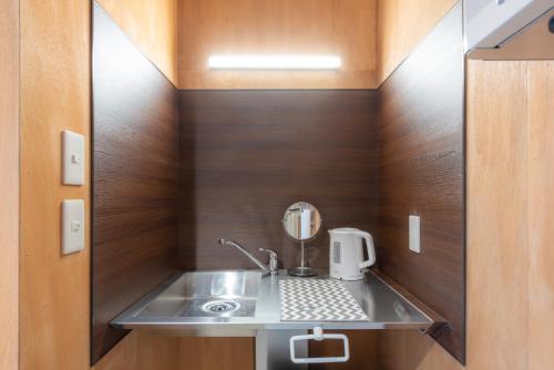 un baño con lavabo y espejo en Ura Otaru Montparnasse Inn, en Otaru