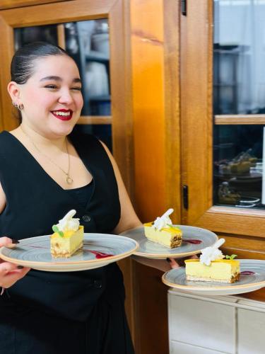a woman is holding two plates of cake at Auberge Le Meisenberg in Châtenois