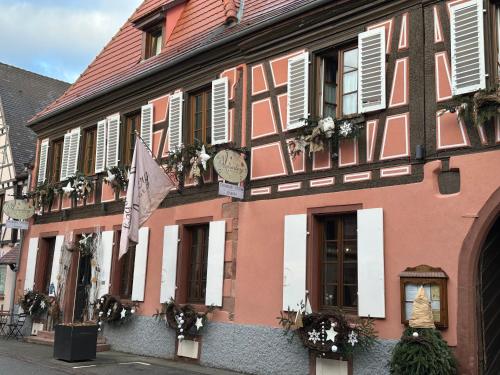 a pink and white building with a clock on it at Auberge Le Meisenberg in Châtenois