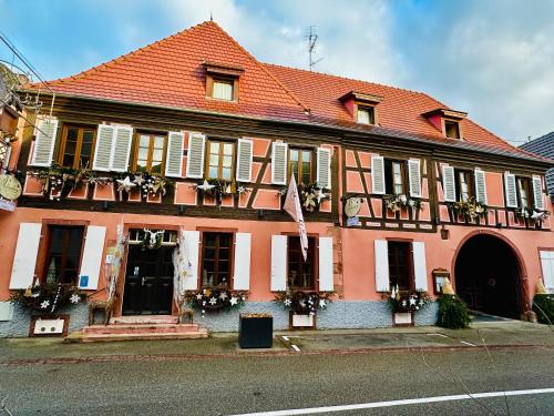 a large pink building with flowers on the windows at Auberge Le Meisenberg in Châtenois