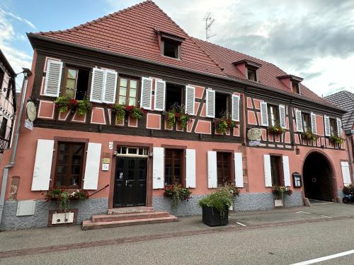 a red building with white shutters and flowers on the windows at Auberge Le Meisenberg in Châtenois