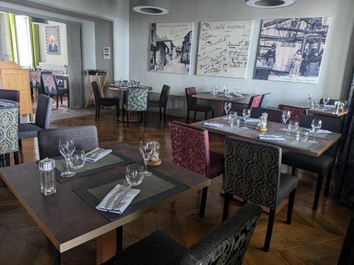 un restaurant avec des tables et des chaises avec des verres à vin dans l'établissement Logis Hôtel Le Tisseur des Saveurs, à Panissières