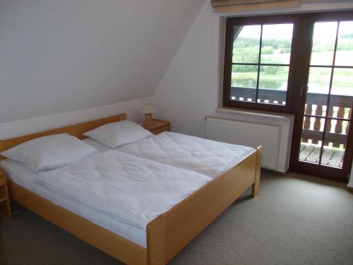 a bedroom with a bed with white sheets and a window at Finnhäuser am Vogelpark - Haus Brigitte in Marlow