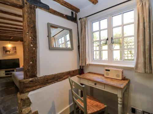 Zimmer mit einem Schreibtisch, einem Fenster und einem Spiegel in der Unterkunft April Cottage in Chipping Campden