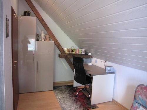 an attic room with a desk and a refrigerator at Ferienwohnung Sabath, 15105 in Leer