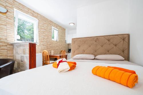 a bedroom with a large white bed with orange objects on it at Apartments Vuković in Kotor