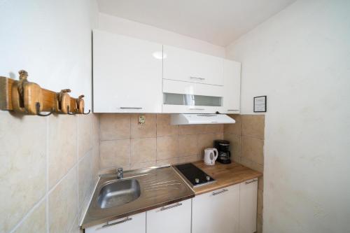 a small kitchen with white cabinets and a sink at Apartments Vuković in Kotor