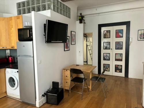 Il comprend une cuisine avec une table et une télévision murale. dans l'établissement 2 bedroom funky apartment in the heart of the old town of Antibes, à Antibes