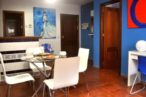 uma sala de jantar com uma mesa e cadeiras brancas em Sevillarent em Sevilha