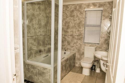 a bathroom with a tub and a toilet and a sink at The Views - Oceanview Haven in Langebaan - 3 Levels of Luxury in Langebaan
