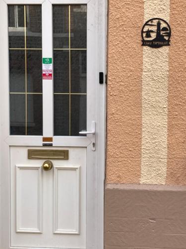 a white door with a sign on the side of a building at Chez Tipoulot - maison de pêcheur à 2 pas du port in Fécamp