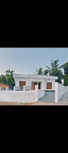 a large white house with trees in the background at HillNest Homes in Ambalavayal