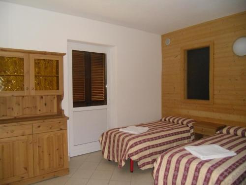 a bedroom with two beds and a dresser and a window at Hotel Residence Bellavista - Camping Polsa in Brentonico