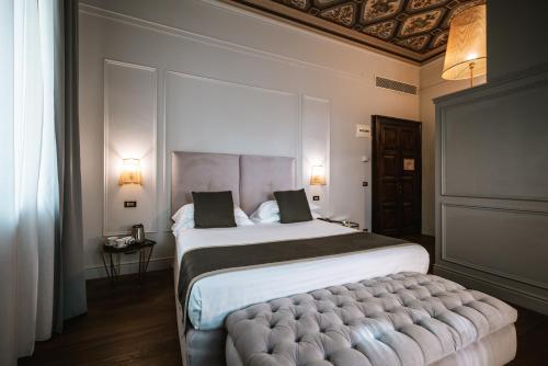 a bedroom with a large bed with a tufted footboard at Hotel De La Ville in Riccione