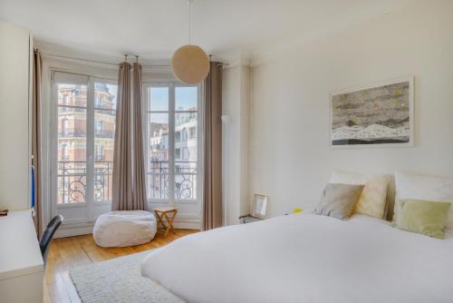 une chambre avec un lit blanc et une grande fenêtre dans l'établissement Paris Les Amandiers Residence, à Paris
