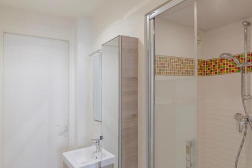 une salle de bain blanche avec un lavabo et une douche dans l'établissement Paris Les Amandiers Residence, à Paris