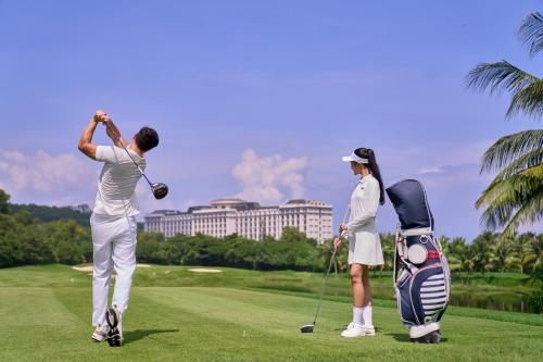 two people playing golf on a golf course at Nha Trang Marriott Resort & Spa, Hon Tre Island in Nha Trang