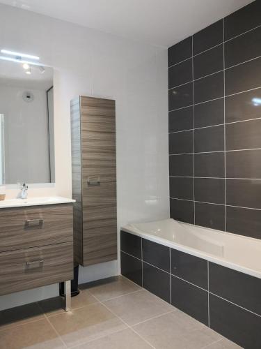 une salle de bain avec une baignoire, un lavabo et un miroir dans l'établissement Très bel appartement 3 pièces 65m2 Villard de Lans avec balcon et jardin, à Villard-de-Lans
