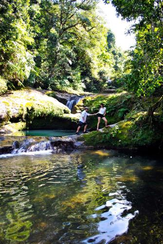 two people are standing in a creek near a waterfall at Hotel Boutique La Casona de Don Porfirio in Jonotla