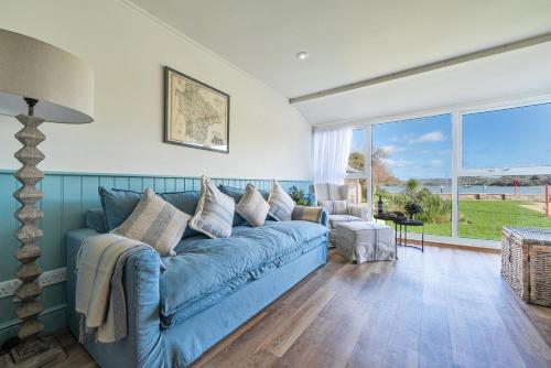 a blue couch in a living room with a large window at Flat 1 The Salcombe in Salcombe