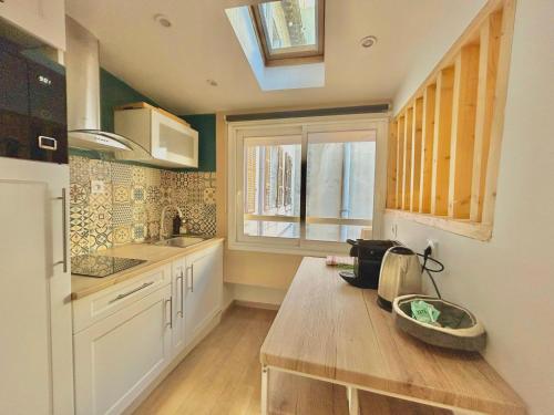 une cuisine avec une table en bois et une fenêtre dans l'établissement Honoré - Rooftop avec vue - Appartement T3 atypique Centre ville Vieux Port proche Opéra, à Marseille
