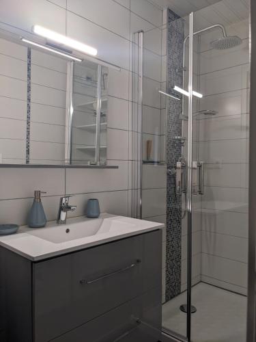 une salle de bain blanche avec un lavabo et une douche dans l'établissement Agréable T2 dernier étage avec balcon & parking - Grenoble Europole, à Grenoble