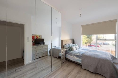 Un dormitorio con una cama, una cómoda y un espejo. en Stylish 3-Bed Townhouse with 3 Baths in Southgate, en Londres