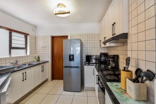 a kitchen with a stainless steel refrigerator and a sink at Ocean Dream Beach Cottage in Swakopmund