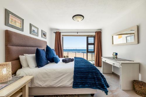 a bedroom with a bed with a desk and a window at Ocean Dream Beach Cottage in Swakopmund