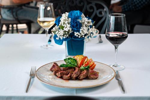 a plate of steak on a table with glasses of wine at Vivid Blue Serenity Resort in Sveti Stefan
