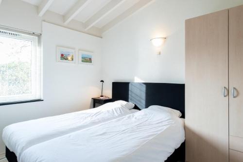 a bedroom with a large bed with white sheets at Valkenhoek (4p) in Ballum
