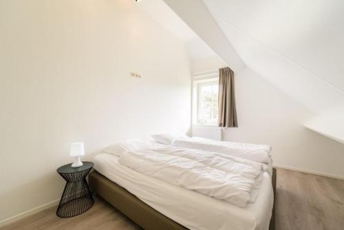 a bed in a white room with a window at Fazant (12p) in Buren