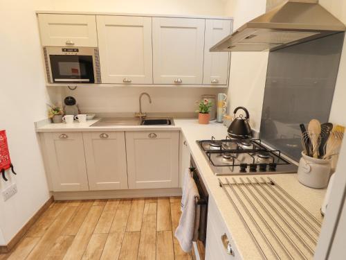 a kitchen with white cabinets and a stove top oven at The Dairy in Brigg