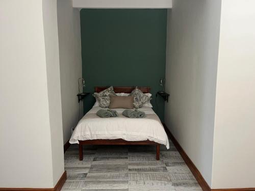 a bedroom with a bed with a green wall at Te Môi in Paarl