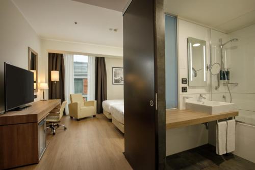 a hotel room with a bathroom with a bed and a sink at DoubleTree By Hilton Milan in Milan