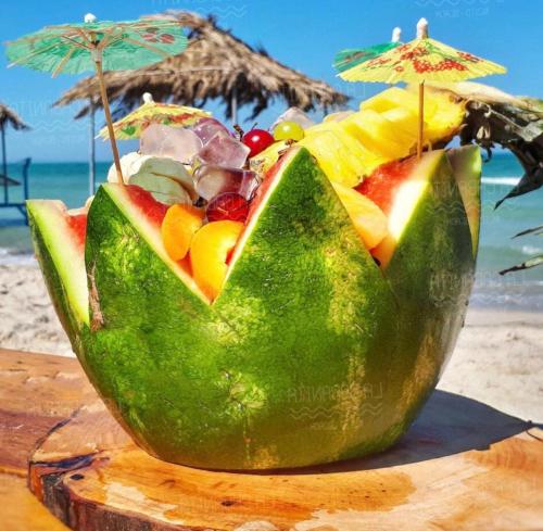 a green avocado cut in half sitting on the beach at Houch Amine in Midoun