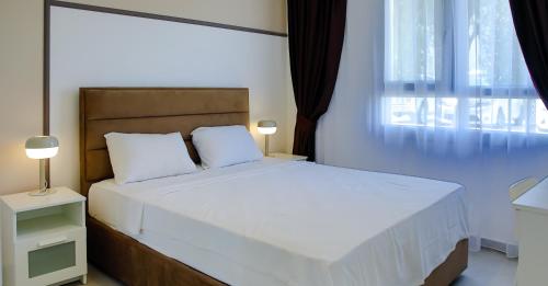 a bedroom with a white bed with a window at Ground Garden View Apartments in Caesar Resort & SPA, Long Beach in Perivolia tou Trikomou