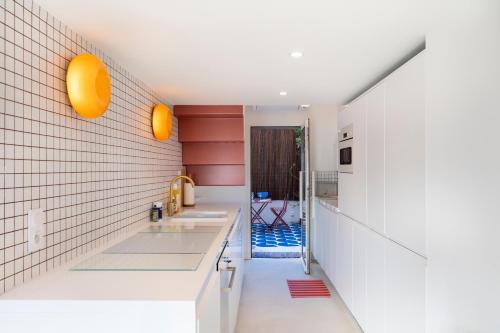 une cuisine avec comptoirs blancs et lumières orange sur le mur dans l'établissement Osea - A 50 mètres du Vieux-Port, à Marseille
