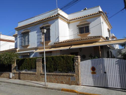a white house with a fence in front of it at Apartamento Caracola in Chipiona