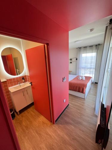 a bedroom with a red wall and a bed and a mirror at Hife Toulouse Sud Labège in Labège