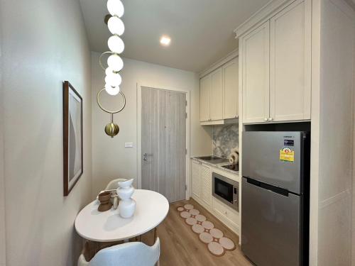 a kitchen with a white table and a refrigerator at DLUX 7TH Floor in Ban Klang