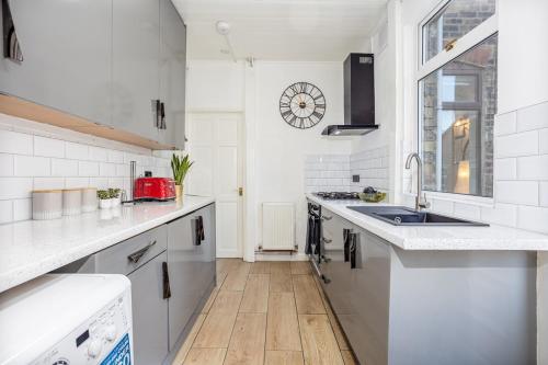 a white kitchen with a sink and a counter at 3 Bedrooms & 2 Showers - Home From Home in Newcastle under Lyme