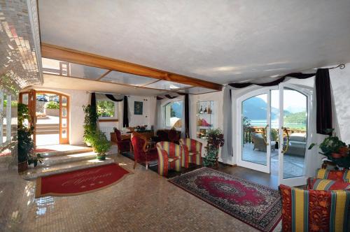 a living room with a table and chairs and a balcony at Hotel Olympia in Molveno