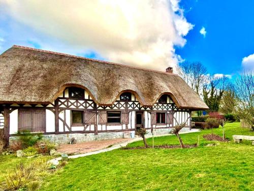 an old house with a thatched roof on a green field at La Charreterie in Auzouville-sur-Saâne
