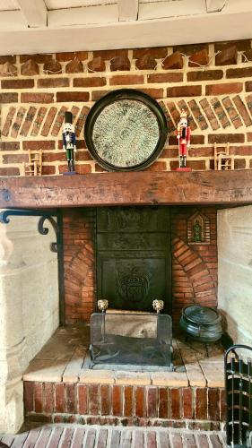 a brick fireplace with a clock on top of it at La Charreterie in Auzouville-sur-Saâne