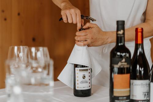 a woman opening a bottle of wine on a table at Hotel Berghaus Rosengarten in Nova Levante