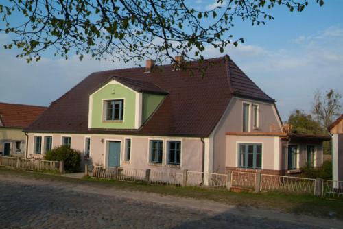 a white house with a brown roof on a street at Auszeit am Haff in Vogelsang